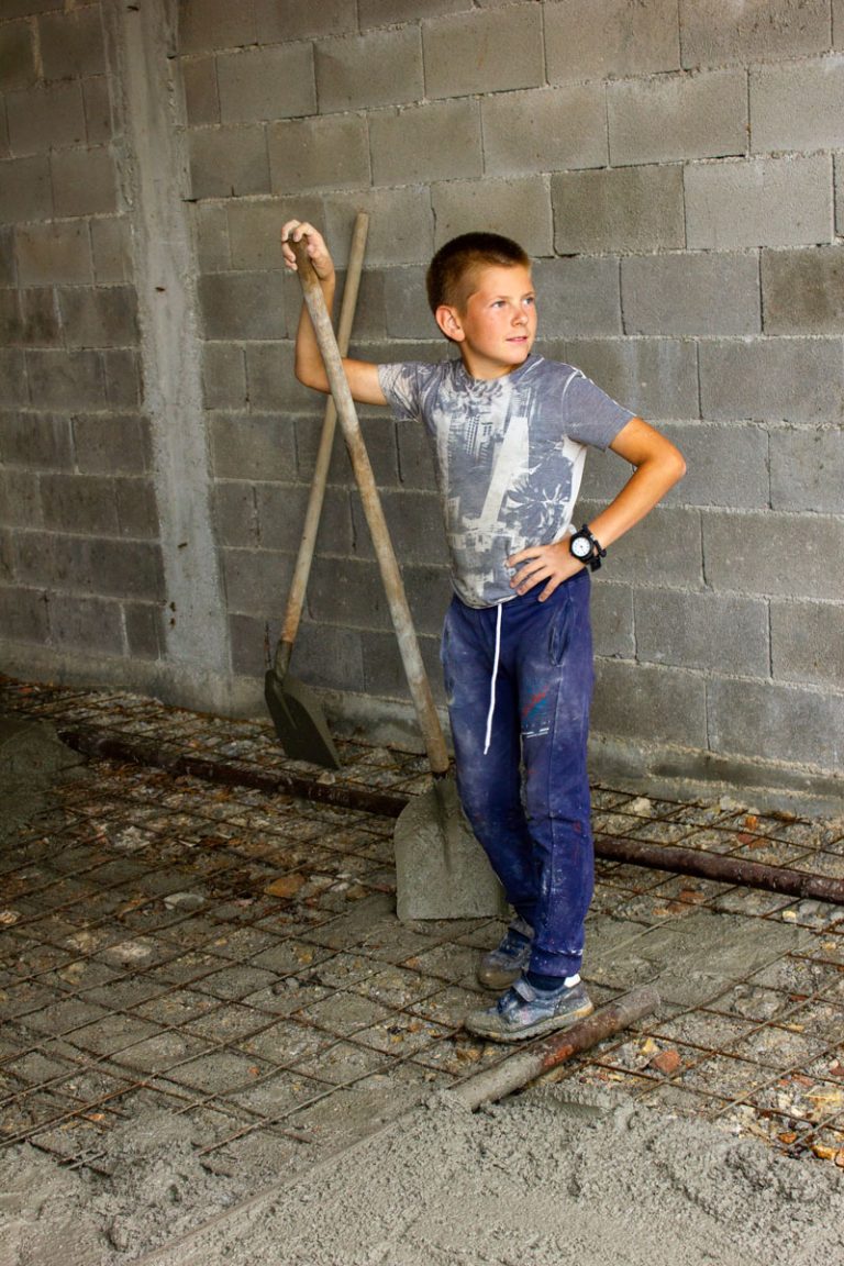 a teenager proud of his work resting on his shovel