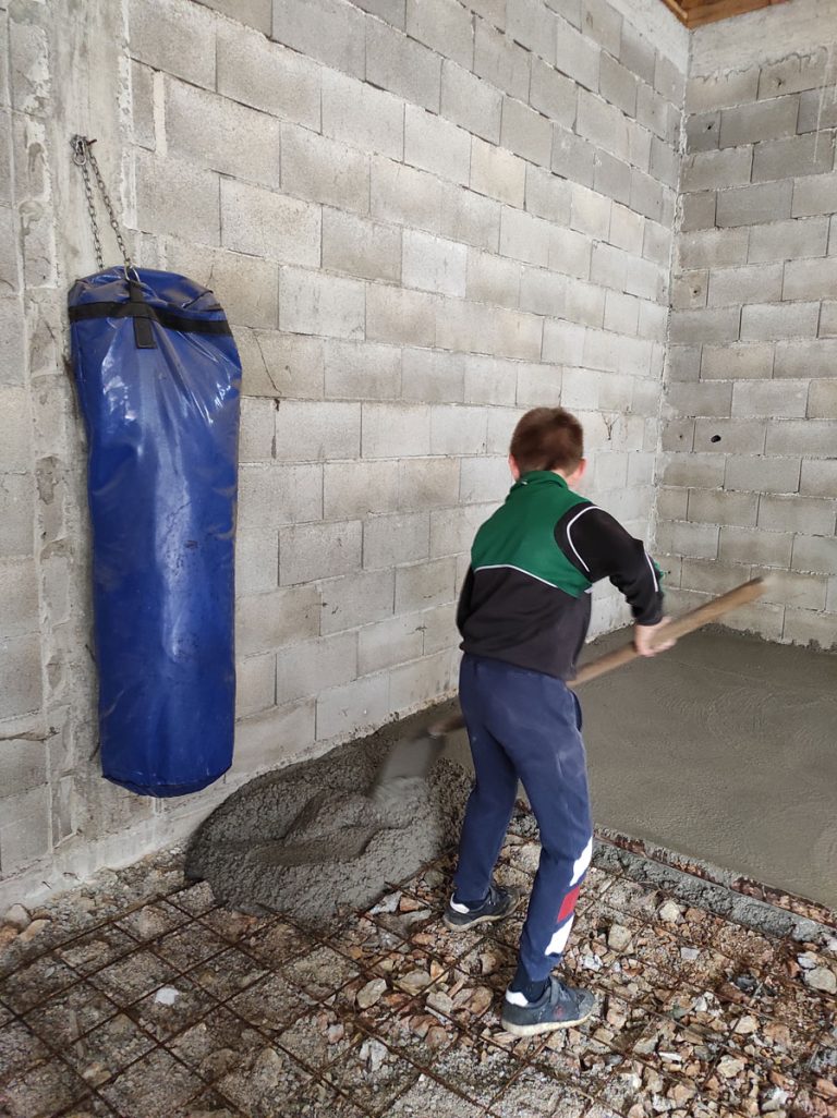 a kid worker leveling concrete in a garage