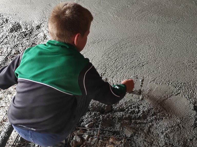 a kid worker leveling concrete in a garage