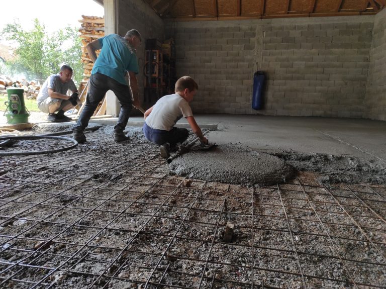 workers pouring and leveling concrete in a garage
