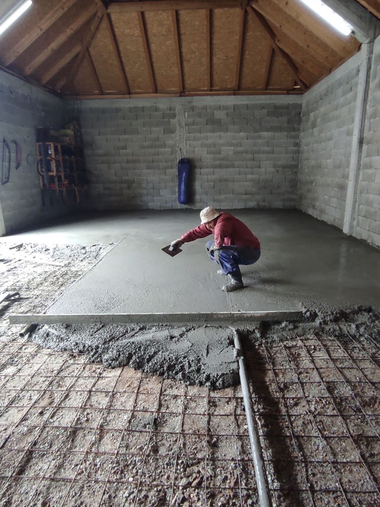 a worker leveling concrete in a garage