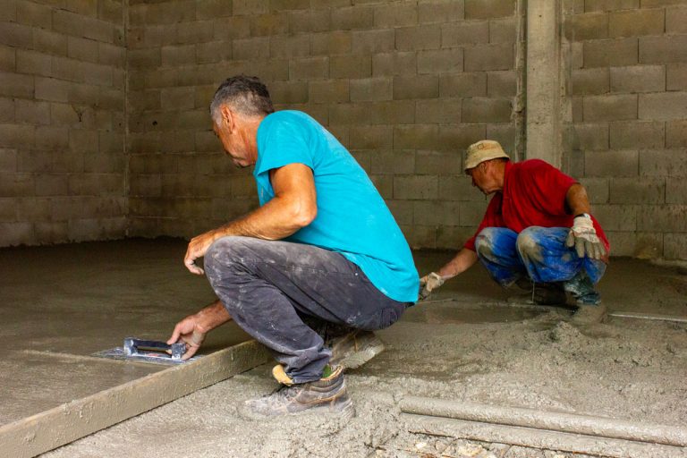 men leveling concrete in a garage