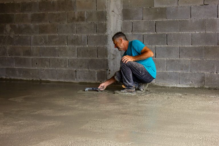 a worker leveling concrete in a garage