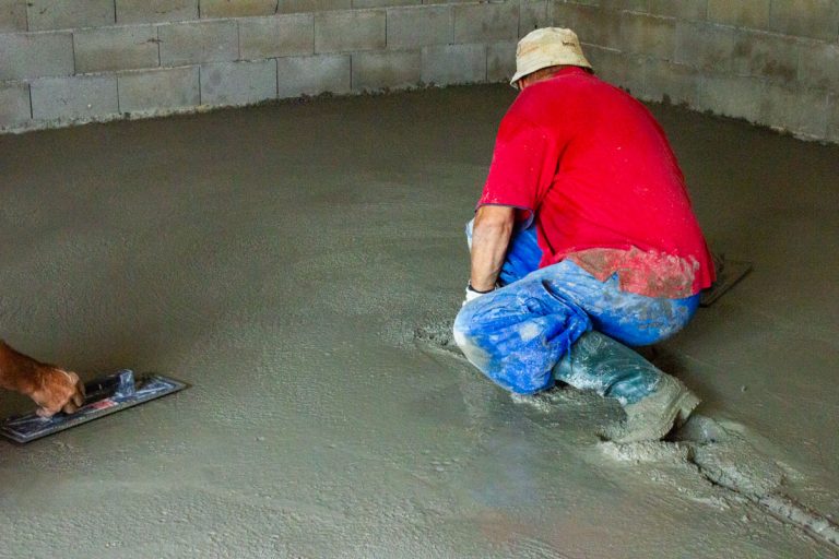 a man leveling concrete in a garage
