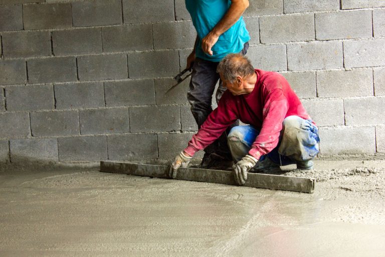 workers leveling concrete in a garage