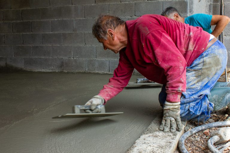 workers leveling concrete in a garage