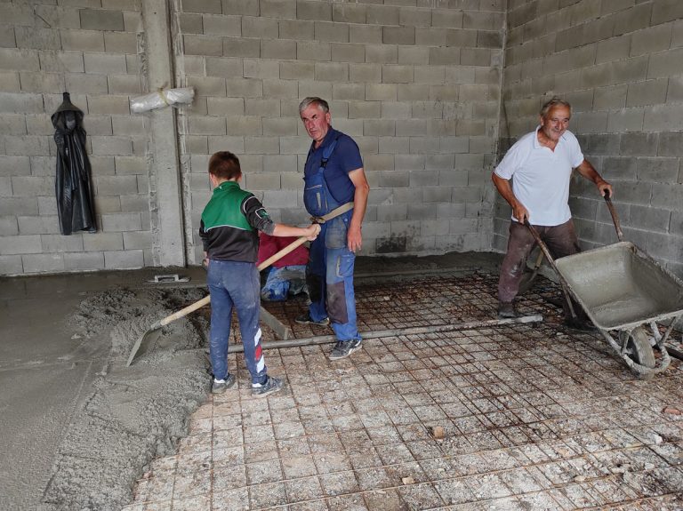 workers pouring and leveling concrete in a garage