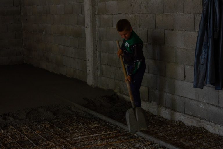 a kid worker leveling concrete in a garage