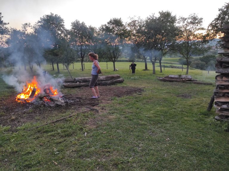 a woman taking a break watching a fire burning a grass collected during the backyard cleaning session