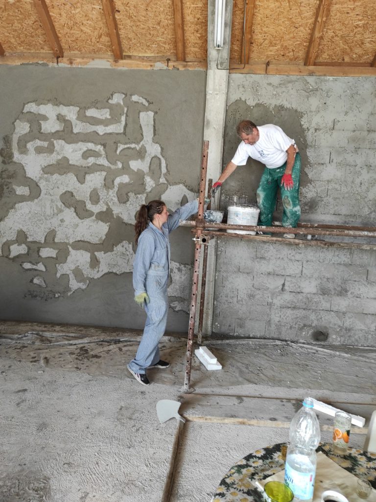 a girl and a worker mortaring the wall