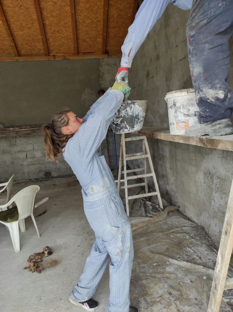 a girl and a worker mortaring the wall