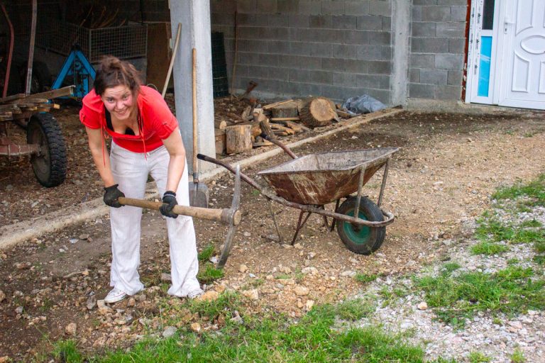 a girl with a pickaxe and a wheelbarrow in front of a garage