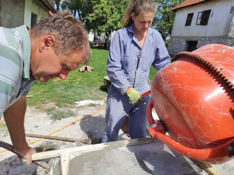a girl and a worker sieving mortar