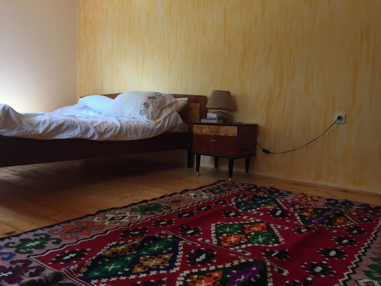 classic old bed with nightstand and traditional kilim
