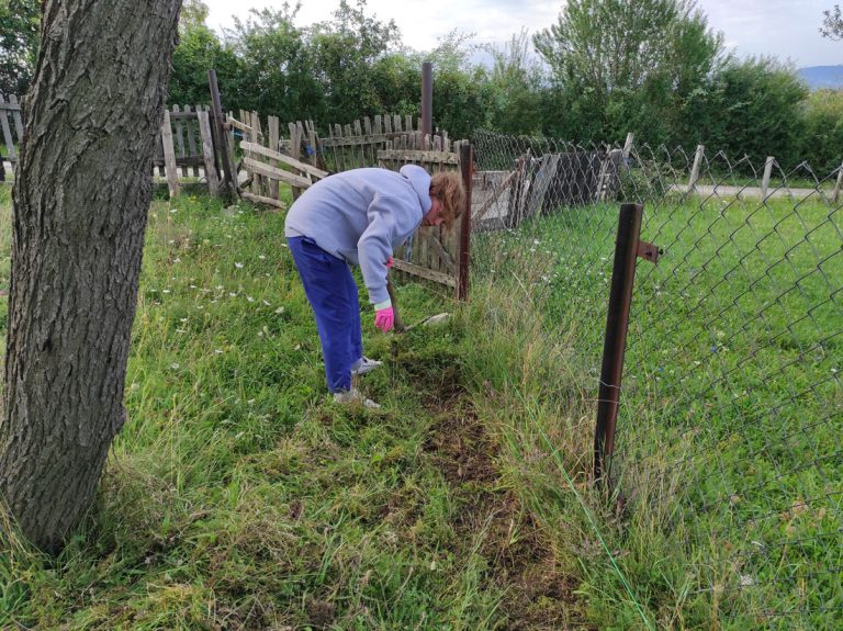 a girl digging dirt by the fence