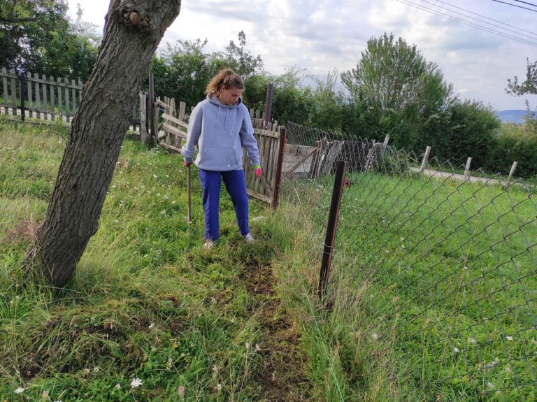 a girl digging dirt by the fence