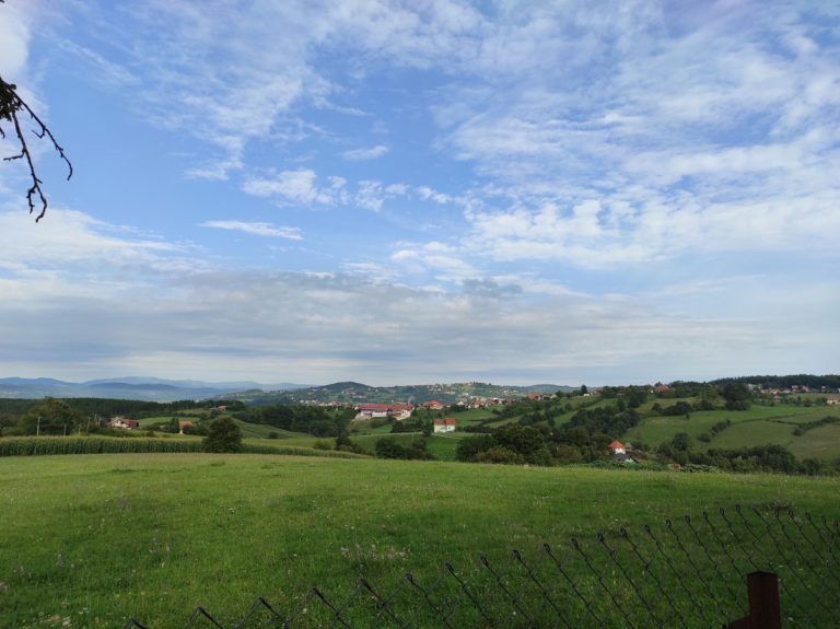 a meadow scenery with a settlement in the distance