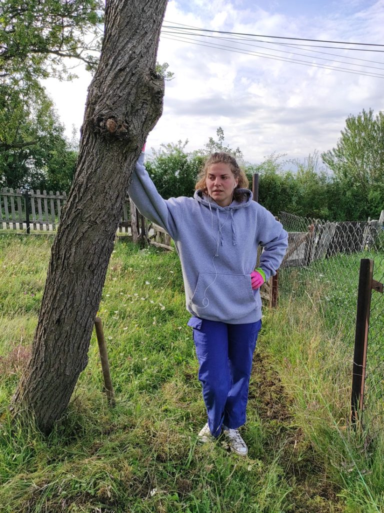 a girl leaning on a tree thinking about her next step in a stone wall making