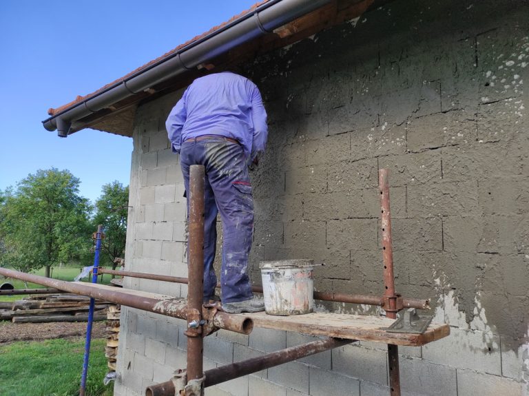 a worker on scaffoldings mortaring the wall