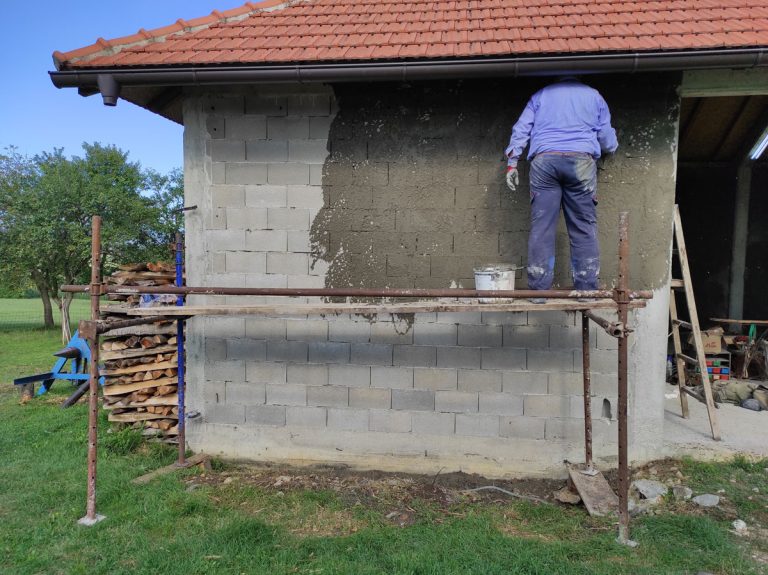 a worker on scaffoldings mortaring the wall