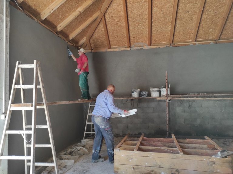 workers on scaffolding mortaring a wall in a garage