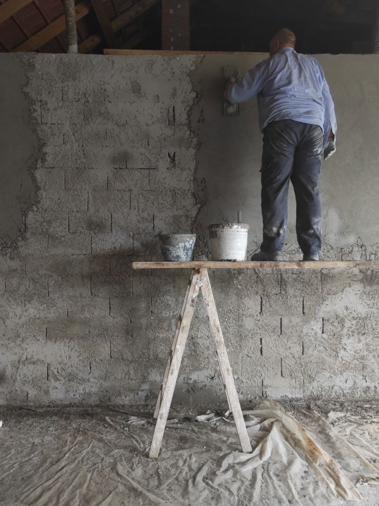 a worker on scaffoldings mortaring the wall