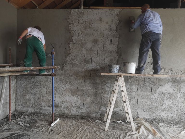 workers on scaffoldings mortaring the wall