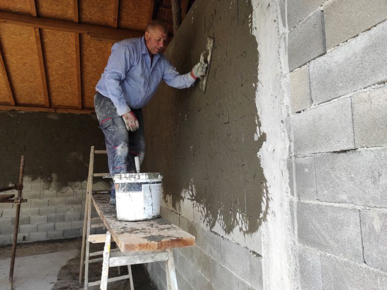 a worker on scaffoldings mortaring the wall