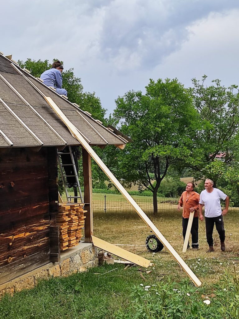 a worker building a new roof on an old wooden cottage