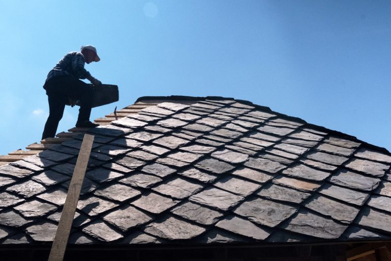 a worker building a new roof tiles on an old wooden cottage