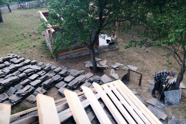workers building a new roof on an old wooden cottage