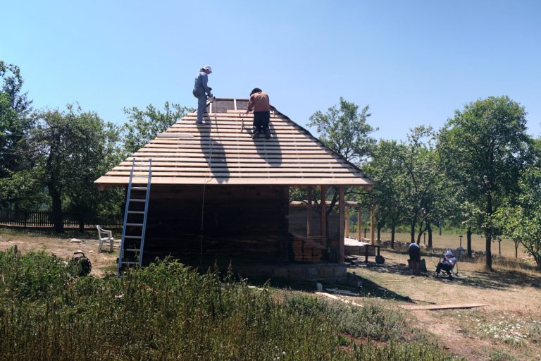 workers building a new roof on an old wooden cottage