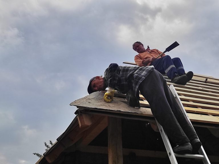 workers building a new roof on an old wooden cottage