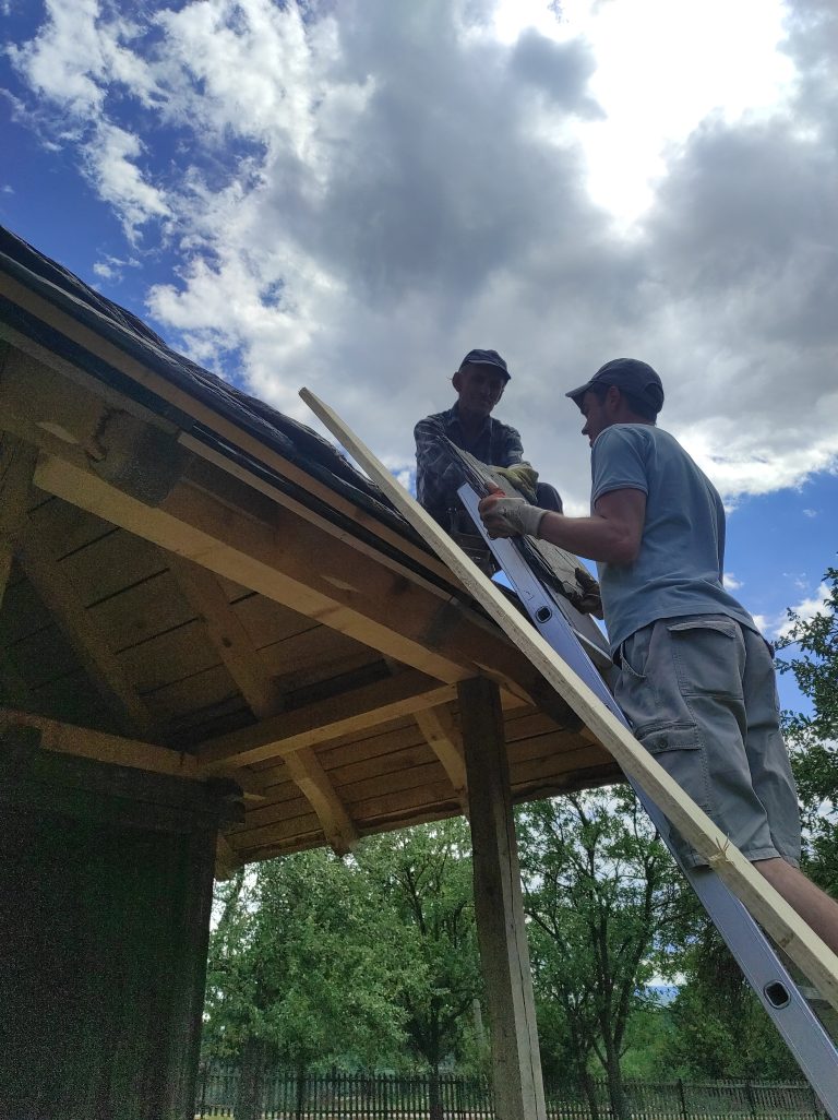 workers building a new roof on an old wooden cottage