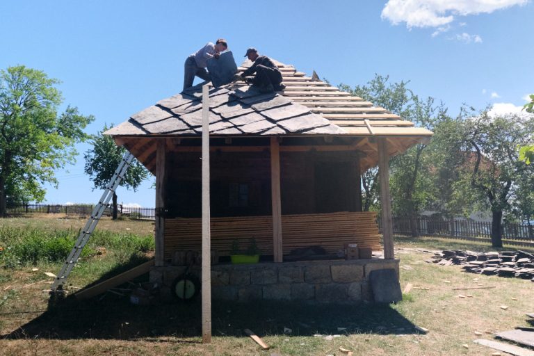 workers building a new roof on an old wooden cottage
