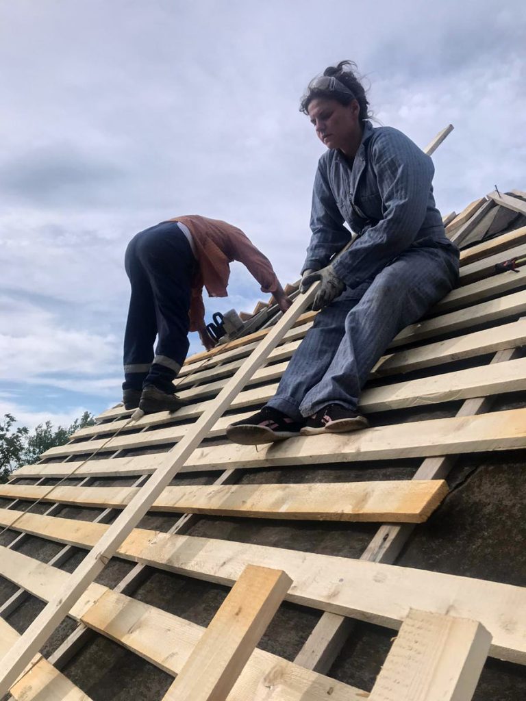 workers building a new roof on an old wooden cottage