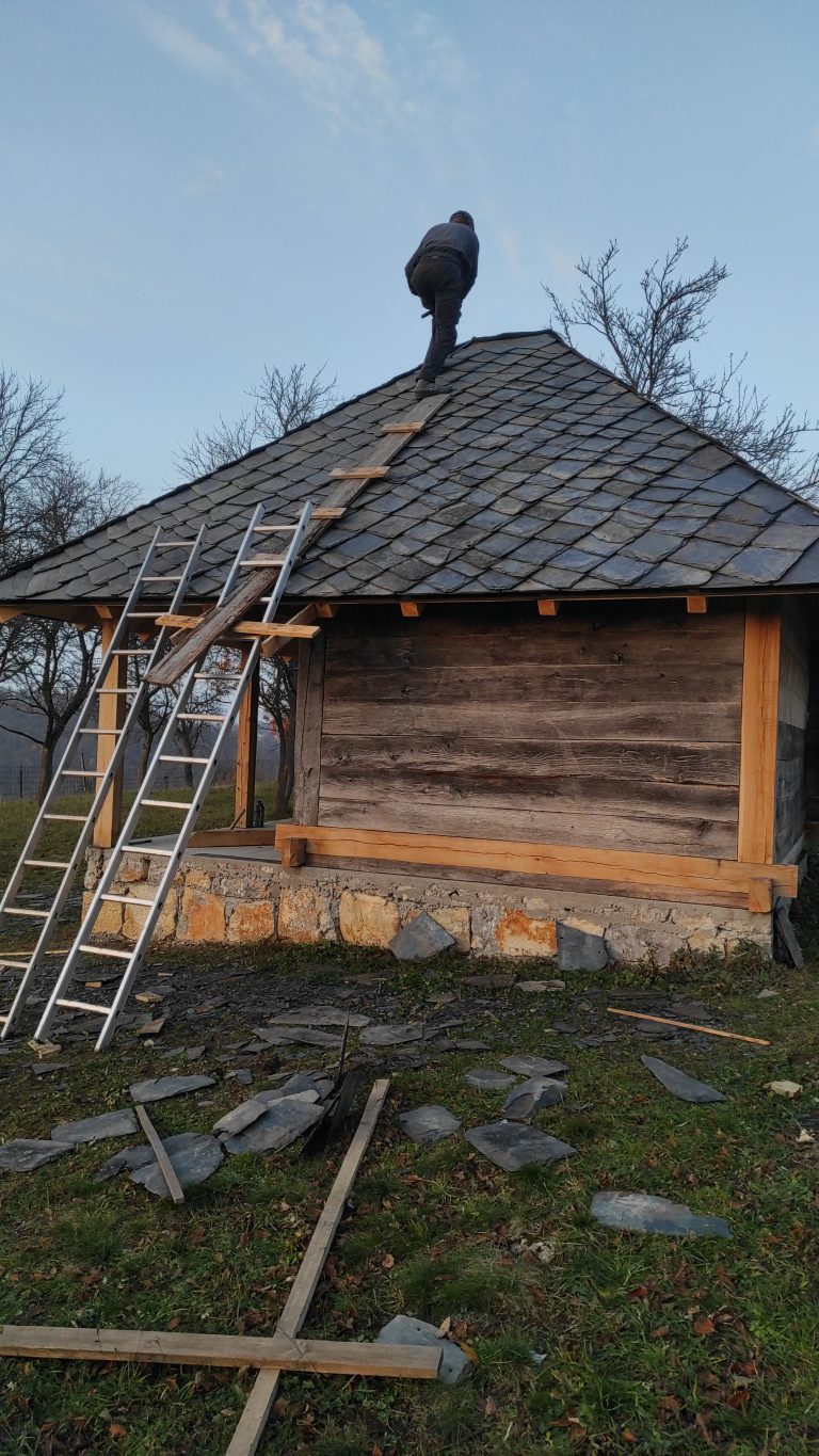 a worker building a new roof on an old wooden cottage