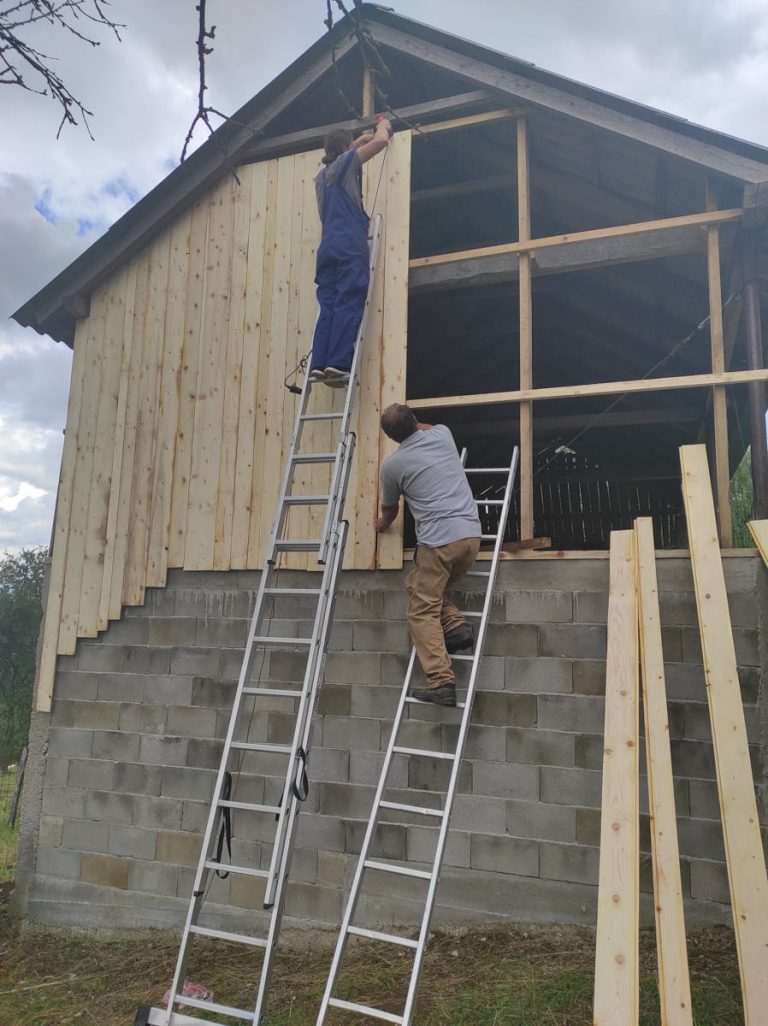 workers building a wooden wall on a hayloft