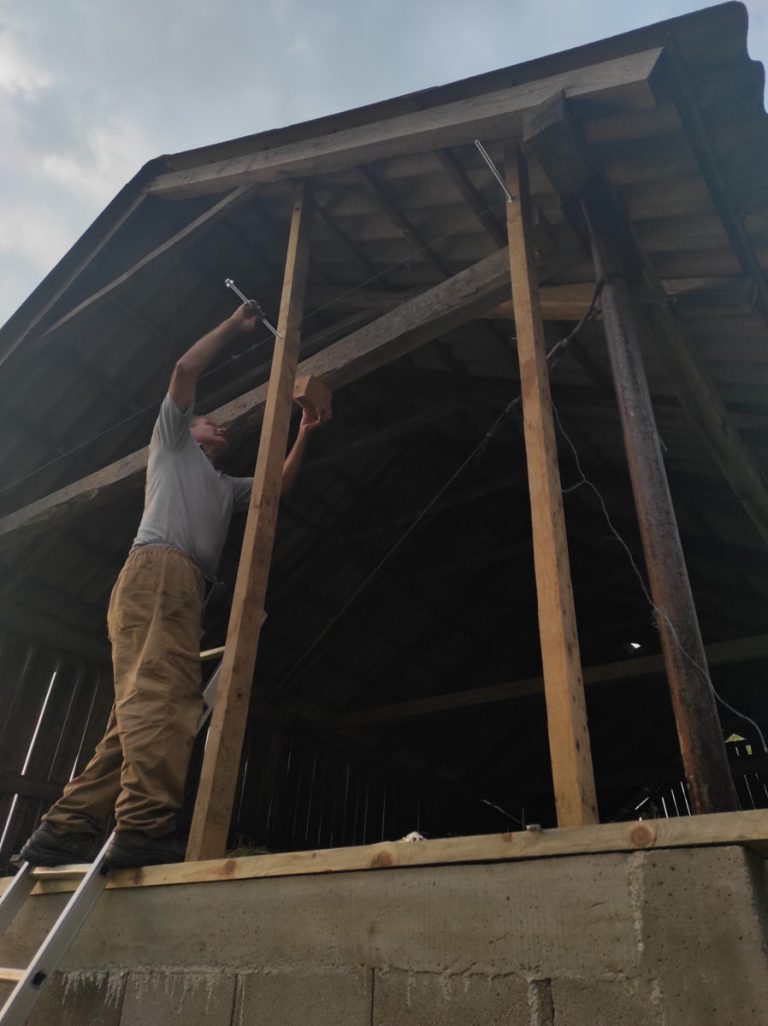 a worker building a wooden wall on a hayloft