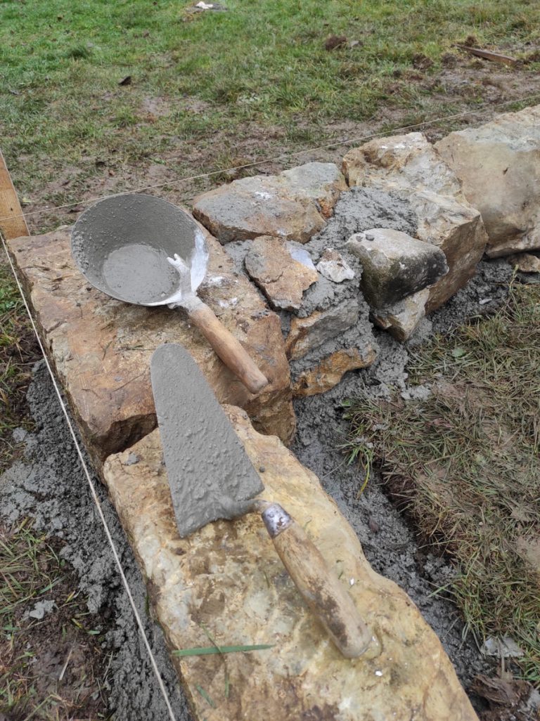 a masonry trowel and a pan on a stone foundation