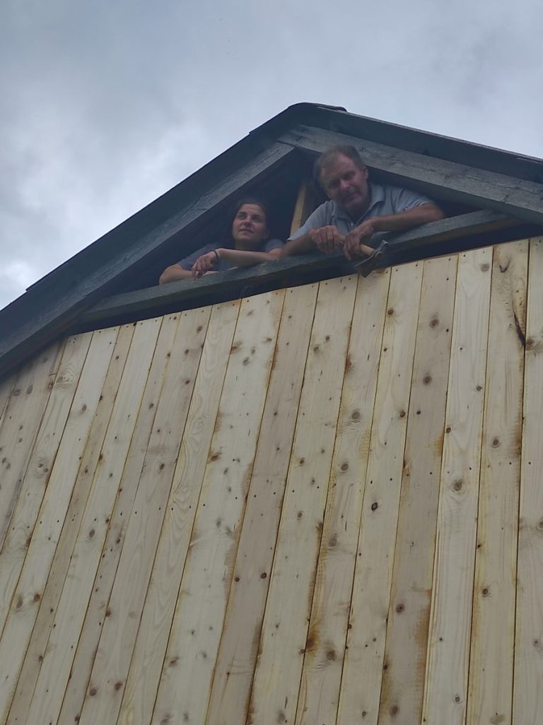 workers building a wooden wall on a hayloft