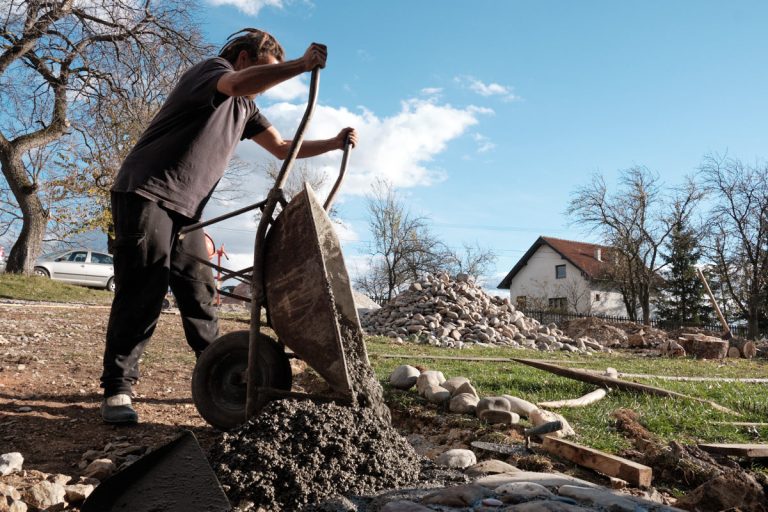 a worker dumbing concrete form a wheelbarrow