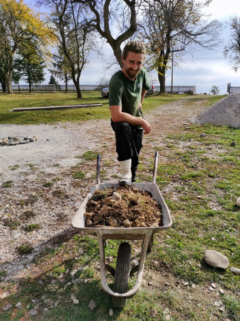 a worker posing on a wheelbarrow full of dirt and gravel