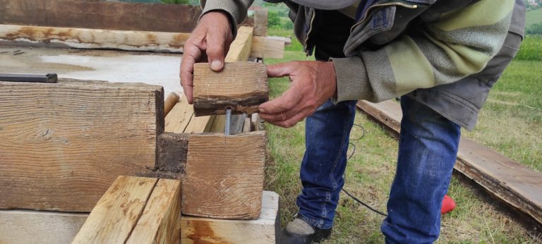 a worker making piles on an old wooden cottage