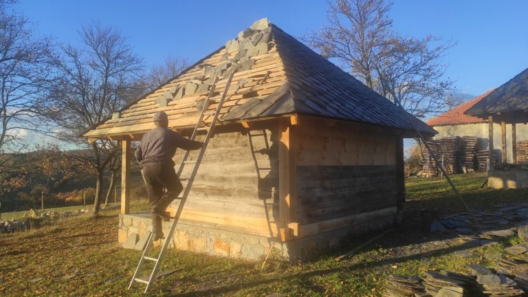 a worker climbing up the ladder to the roof of an old wooden cottage
