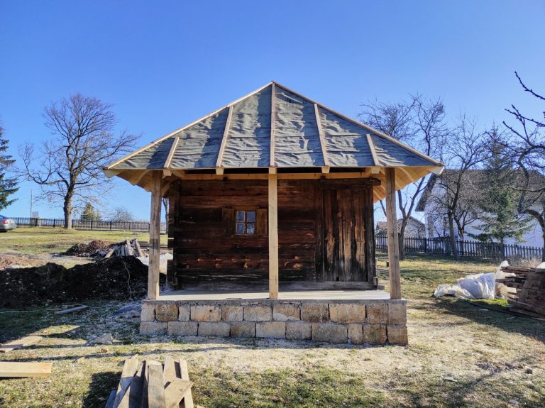 an old wooden cottage with stone foundation and a new roof