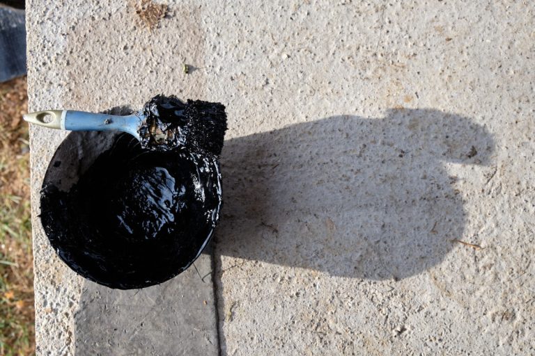 a brush and a bucket of melted bitumen