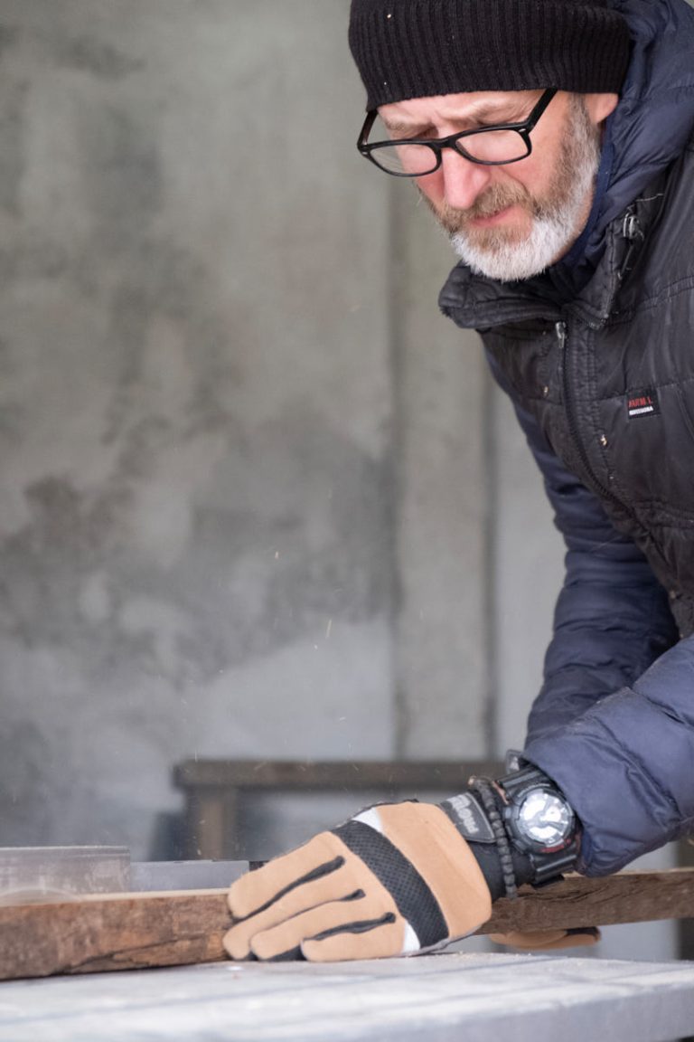 a worker cutting a wooden plate on a table saw