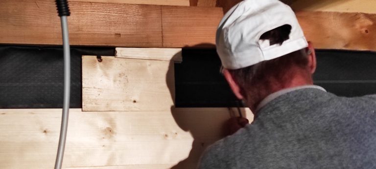 a worker installing the insulation in a wooden cottage