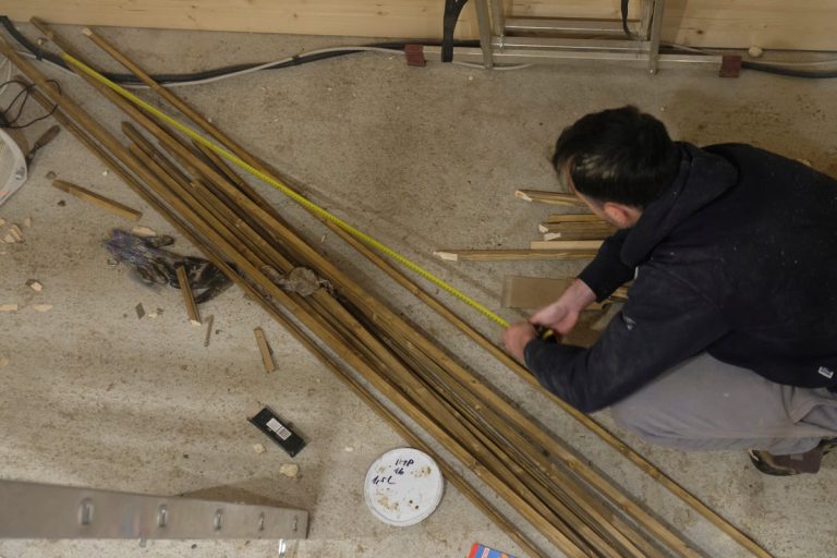 a man measuring wooden sticks